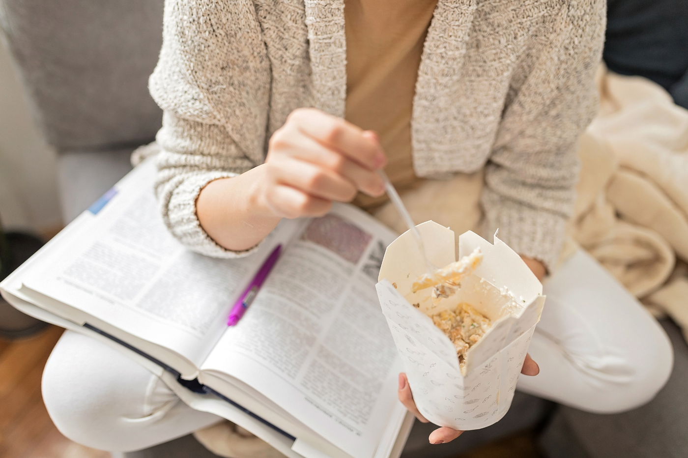 jeune femme mangeant un pot de pâtes en étudiant